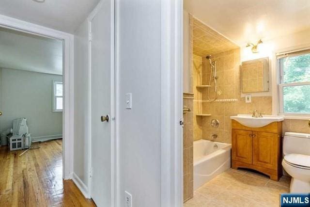 bathroom with baseboards, toilet, shower / bathtub combination, tile patterned flooring, and vanity