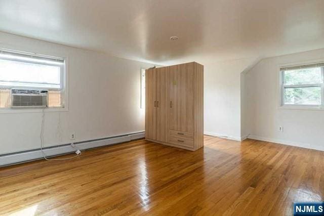 bonus room featuring a baseboard heating unit, cooling unit, baseboards, and wood finished floors