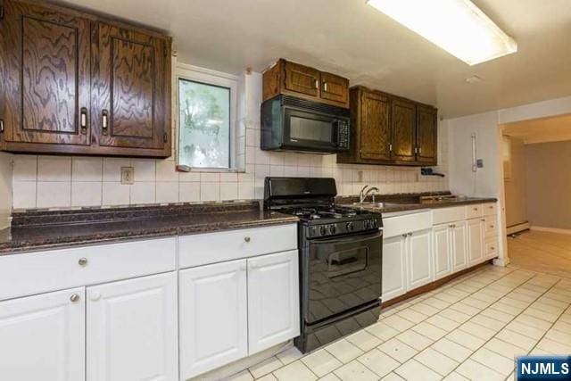 kitchen with light tile patterned floors, tasteful backsplash, white cabinets, a sink, and black appliances