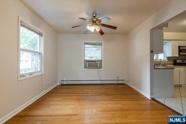 spare room featuring light wood-type flooring, cooling unit, plenty of natural light, and baseboard heating