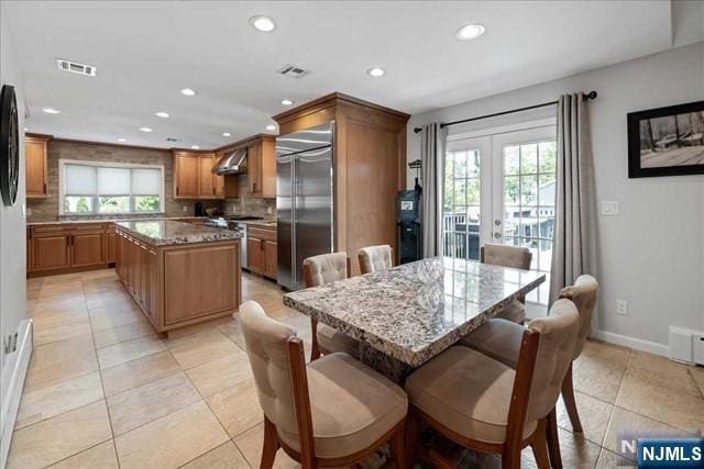 kitchen featuring built in refrigerator, a kitchen island, visible vents, and a healthy amount of sunlight