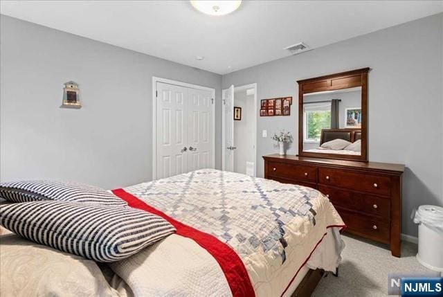 bedroom with visible vents, a closet, and light colored carpet