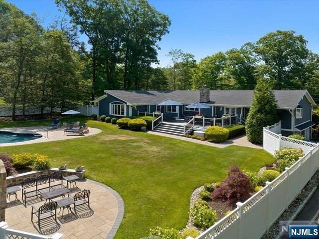 rear view of house featuring a patio, a fenced backyard, a yard, a fenced in pool, and a chimney