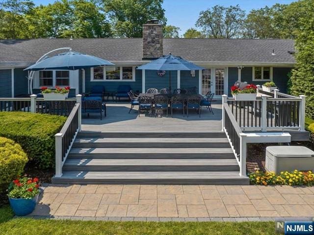 back of house with french doors, a chimney, a wooden deck, and outdoor dining area