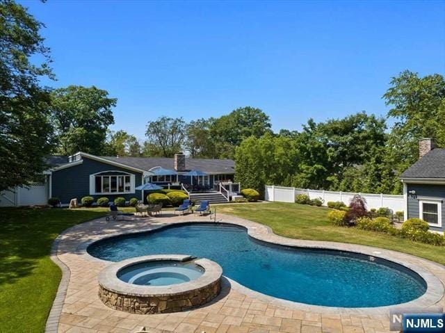 view of pool featuring a pool with connected hot tub, a fenced backyard, a lawn, and a patio