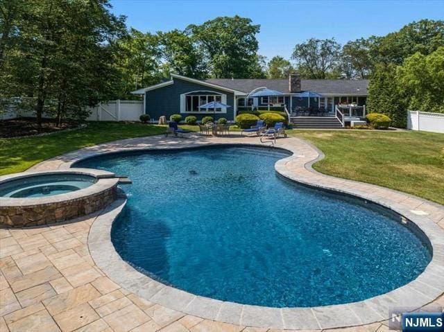 view of pool featuring a yard, a patio, a fenced backyard, and a pool with connected hot tub