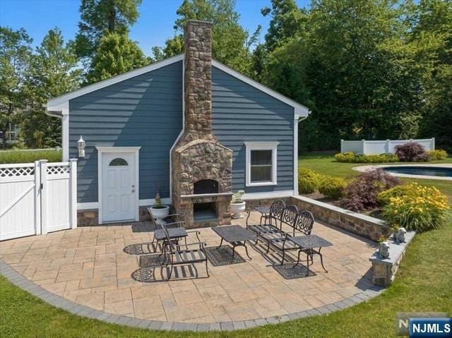 view of patio / terrace featuring fence and an outdoor stone fireplace