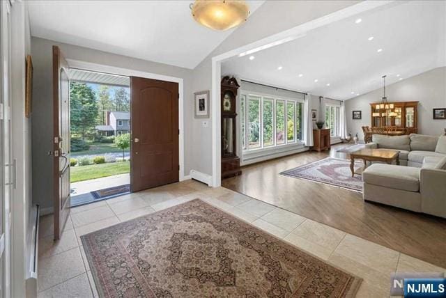 foyer with plenty of natural light, light tile patterned flooring, vaulted ceiling, and baseboards