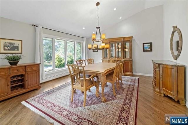 dining room featuring light wood-type flooring, vaulted ceiling, baseboards, and recessed lighting