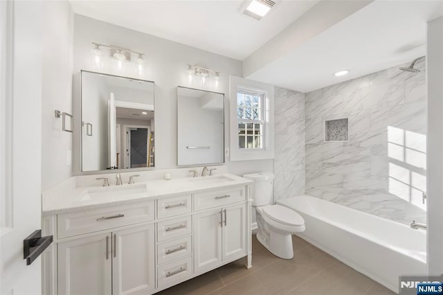 full bathroom with toilet, double vanity, visible vents, and a sink