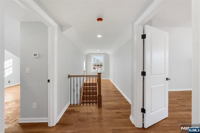 hall featuring wood finished floors, an upstairs landing, and baseboards