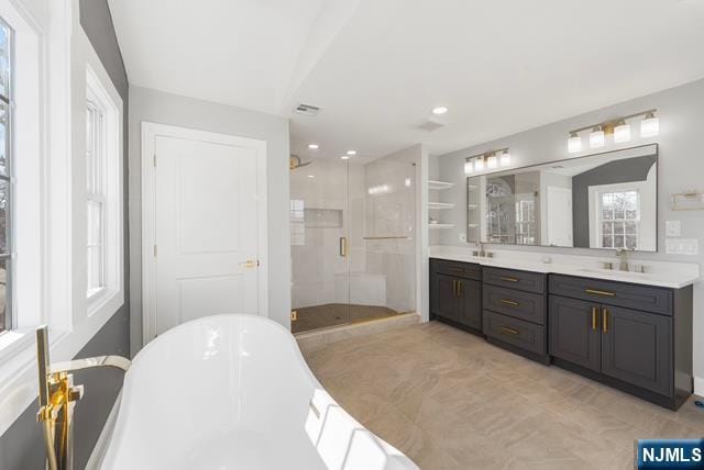 bathroom featuring a stall shower, a sink, a freestanding bath, and double vanity