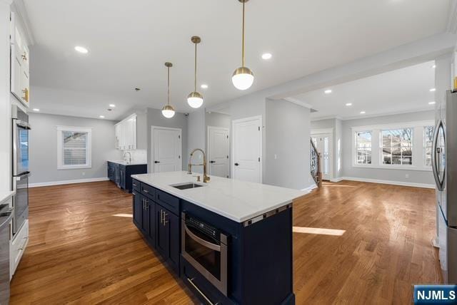 kitchen with light countertops, white cabinetry, a sink, wood finished floors, and blue cabinets