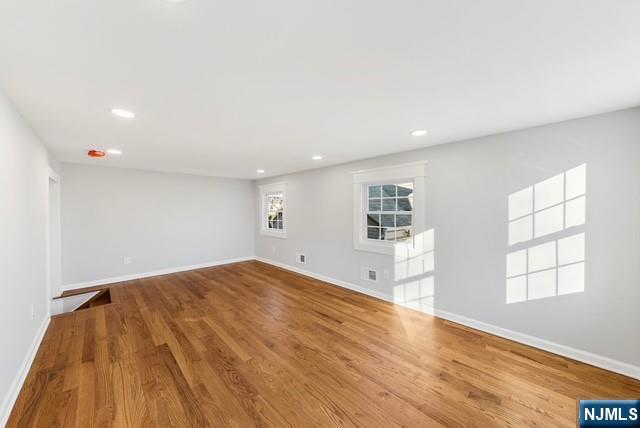 unfurnished room with recessed lighting, wood finished floors, and baseboards