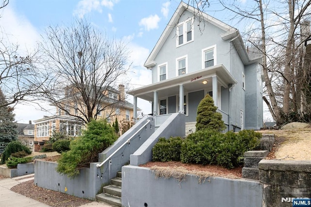 view of front of house with covered porch, stairway, and stucco siding