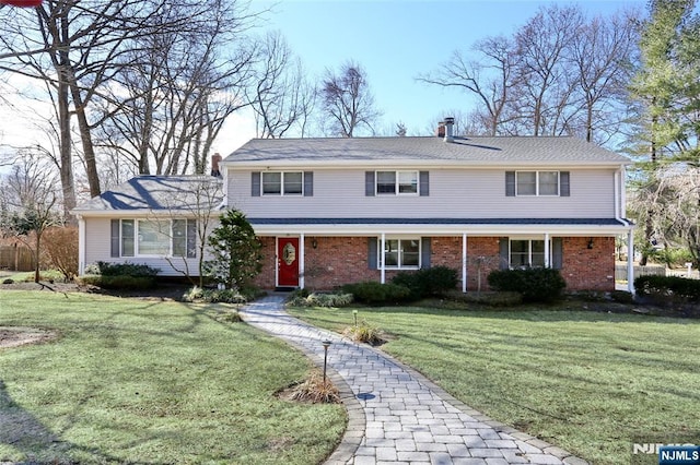 traditional home with brick siding, a chimney, and a front lawn