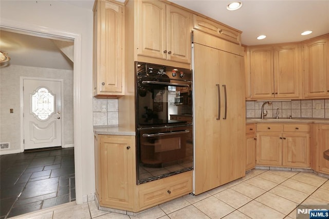 kitchen featuring light brown cabinetry, fridge, a sink, and dobule oven black