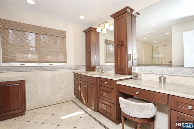 full bath featuring a shower with door, tile walls, recessed lighting, vanity, and ornate columns