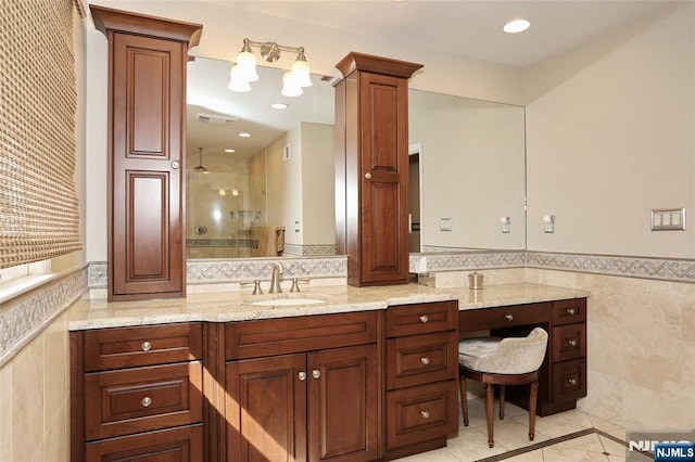 bathroom with visible vents, wainscoting, walk in shower, vanity, and tile walls