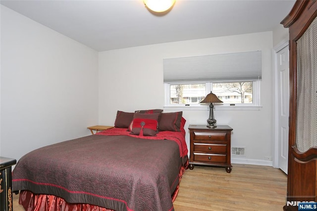 bedroom with visible vents, baseboards, and wood finished floors