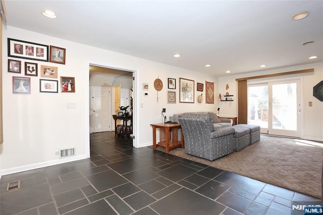 living area with recessed lighting, stone tile flooring, visible vents, and baseboards