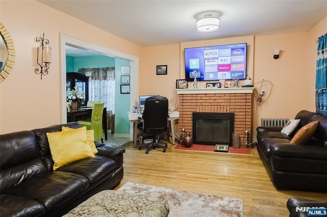 living room with radiator, a fireplace, and wood finished floors