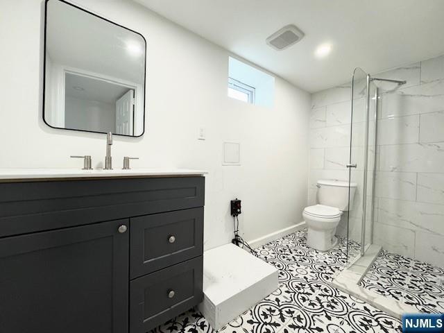 bathroom with vanity, toilet, a stall shower, baseboards, and tile patterned flooring