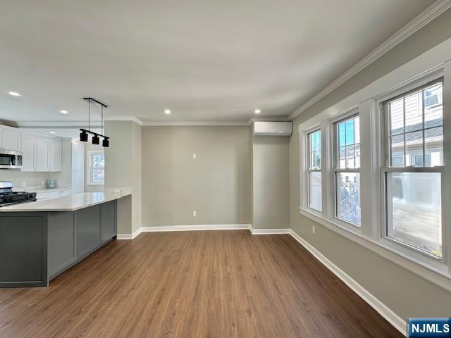 kitchen with crown molding, dark wood-style flooring, appliances with stainless steel finishes, and baseboards