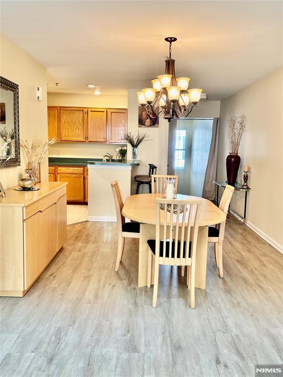 dining area with a notable chandelier, light wood-style flooring, and baseboards