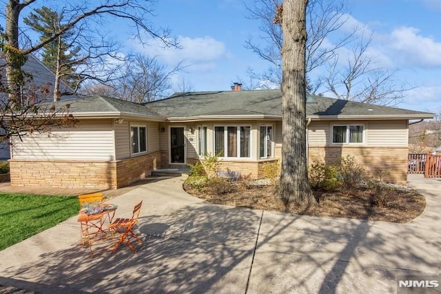 view of front of home featuring a chimney and brick siding