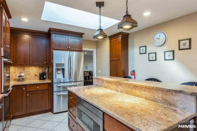 kitchen with tasteful backsplash, light stone counters, hanging light fixtures, stainless steel appliances, and light tile patterned flooring