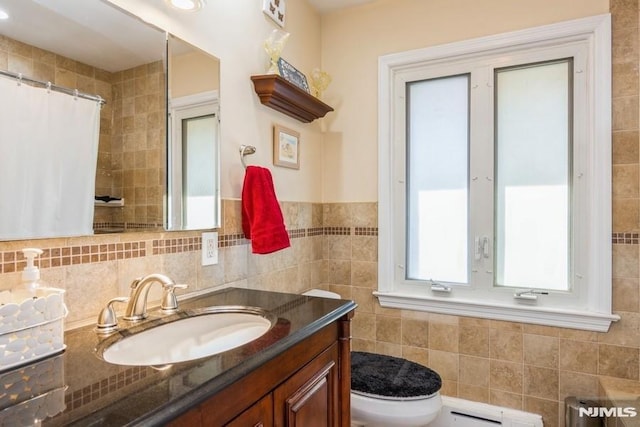 full bath with toilet, a baseboard radiator, curtained shower, vanity, and tile walls