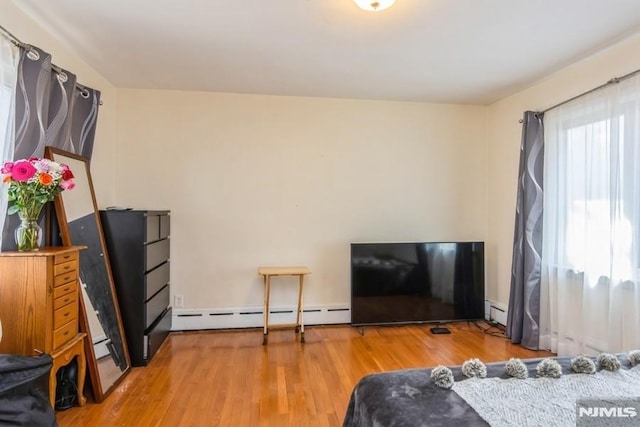 bedroom featuring a baseboard heating unit and wood finished floors