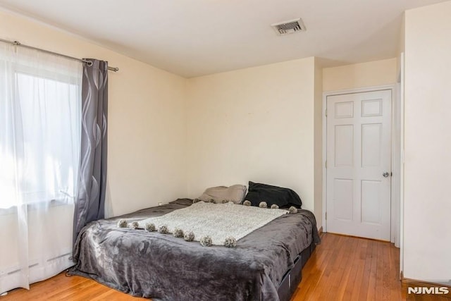 bedroom featuring light wood-style floors, visible vents, and baseboard heating