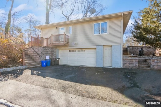 back of property with driveway, an attached garage, and stairs