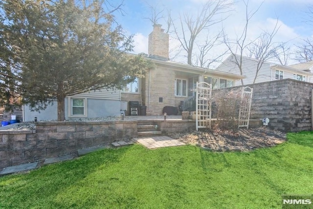 rear view of house featuring a chimney, a patio, and a yard