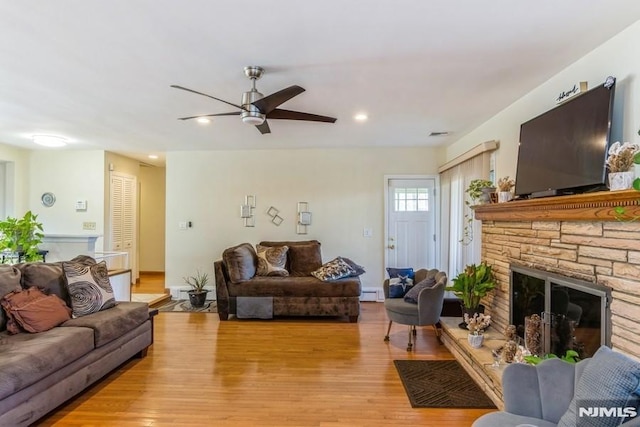 living room with ceiling fan, light wood-style flooring, recessed lighting, a fireplace, and baseboard heating