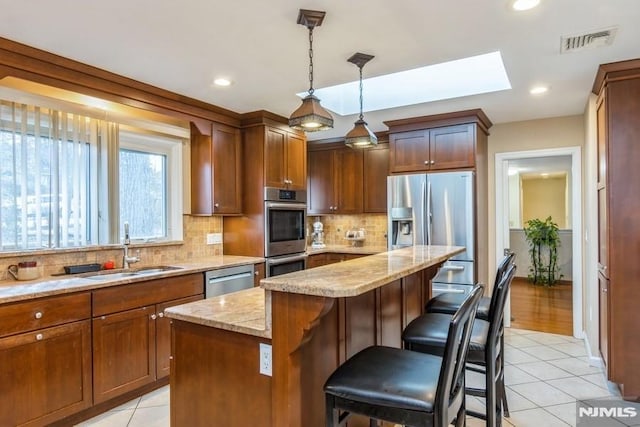 kitchen with light tile patterned floors, stainless steel appliances, a skylight, a sink, and visible vents