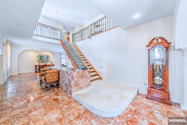 stairway featuring arched walkways, recessed lighting, and baseboards