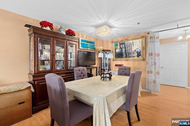 dining room featuring light wood-type flooring, baseboards, and an inviting chandelier