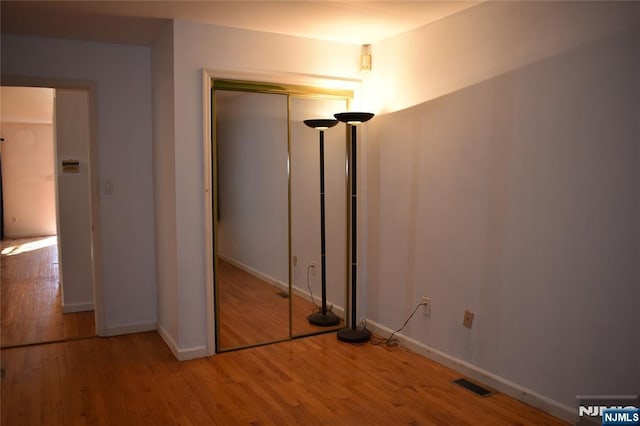 unfurnished bedroom with baseboards, a closet, visible vents, and wood finished floors