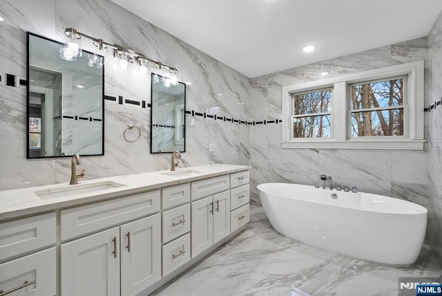 bathroom with marble finish floor, a sink, a freestanding bath, and double vanity