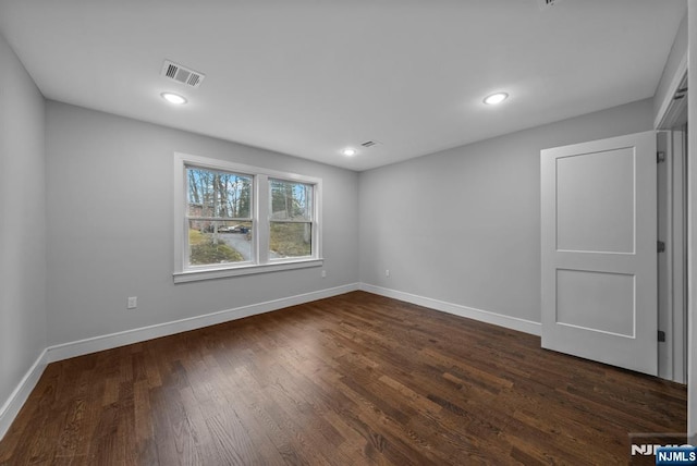 spare room featuring dark wood-style floors, visible vents, baseboards, and recessed lighting