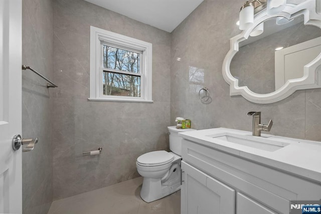 bathroom featuring tile walls, toilet, and vanity