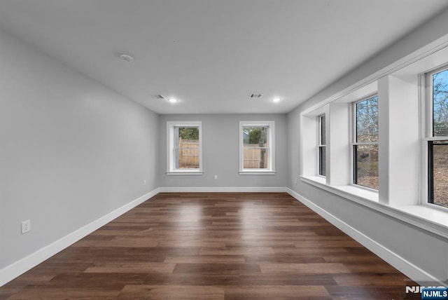 unfurnished room with dark wood-type flooring, recessed lighting, visible vents, and baseboards