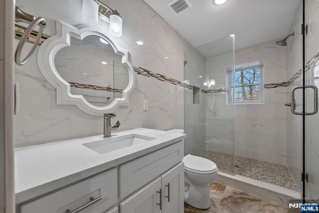 full bathroom featuring toilet, a marble finish shower, visible vents, and vanity