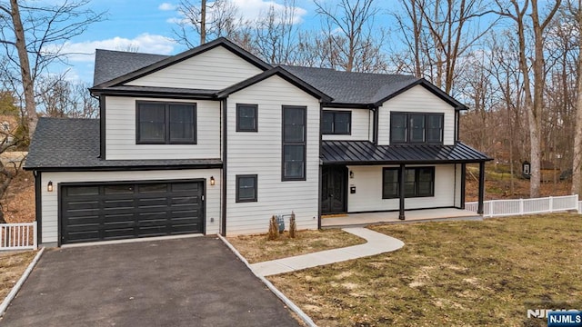 view of front of house with driveway, metal roof, covered porch, a standing seam roof, and fence