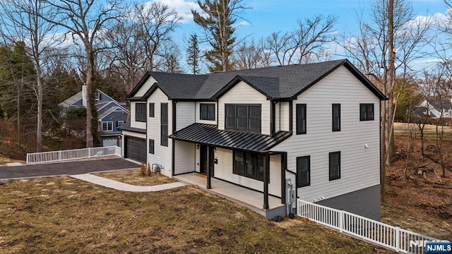 view of front of house with aphalt driveway, covered porch, a standing seam roof, metal roof, and a garage