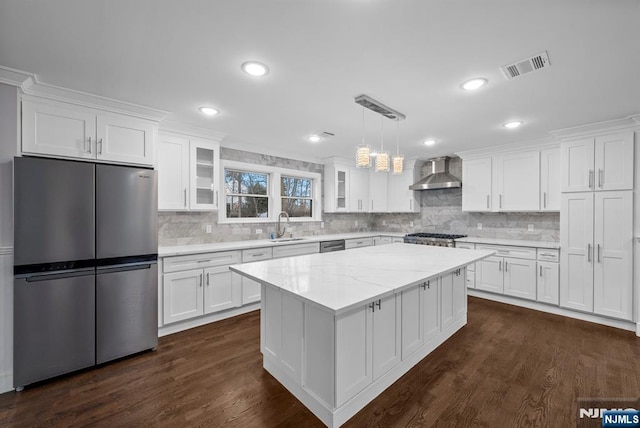 kitchen with visible vents, white cabinets, wall chimney exhaust hood, glass insert cabinets, and appliances with stainless steel finishes