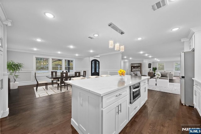 kitchen featuring stainless steel appliances, open floor plan, a center island, plenty of natural light, and crown molding